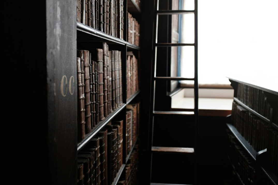 Old library with tall wooden shelves full of books